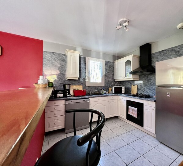 A modern kitchen with white cabinets, a black stove, and a stainless steel refrigerator.