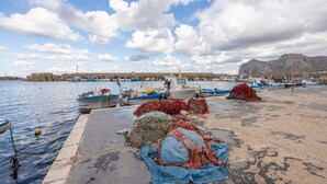 A harbor with boats, fishing nets, and a mountainous backdrop. - Casa Lucid'amare Relaxation with Private Terrace, Wi-Fi & Air Conditioning (isola delle femmine)