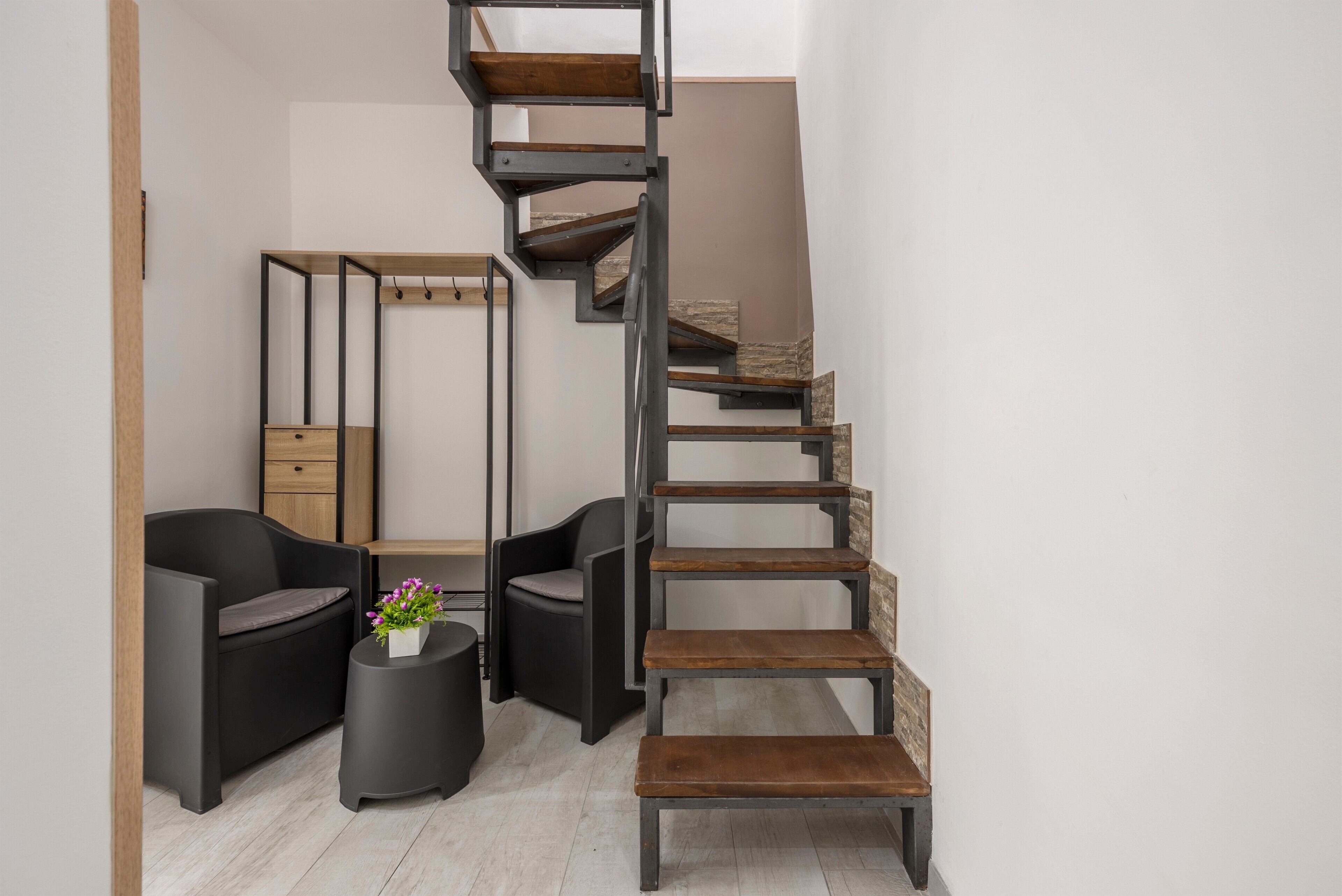 Un intérieur moderne avec un escalier en colimaçon, des meubles noirs et une petite table ronde agrémentée de fleurs.