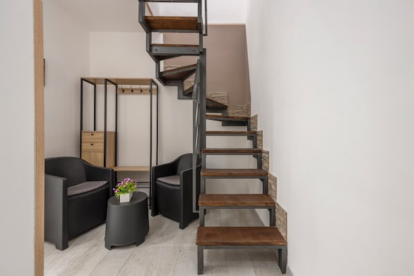 Un intérieur moderne avec un escalier en colimaçon, des meubles noirs et une petite table ronde agrémentée de fleurs.