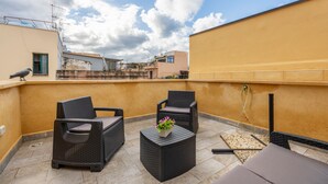 A rooftop terrace with two wicker chairs, a small table with a flower, and a view of neighboring buildings. - Casa Lucid'amare Relaxation with Private Terrace, Wi-Fi & Air Conditioning (isola delle femmine)