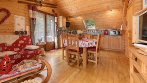 A wooden interior with a dining area, kitchen, and a cozy living space.