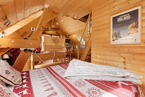 Ein Holzblockhaus-Innenraum mit einem Bett, einem Essbereich und einem Bild an der Wand.