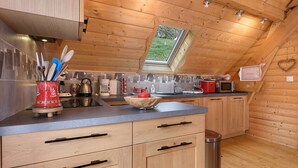 A kitchen with wooden cabinets, a countertop, a window, and a heart-shaped decoration on the wall.