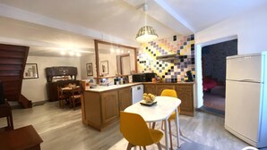 Une cuisine compacte avec un coin repas, des meubles en bois, un pare-feu en carrelage et un luminaire suspendu moderne.