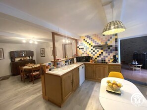 Een kleine keuken met een centraal eiland, houten kastjes en een betegelde spatwand.