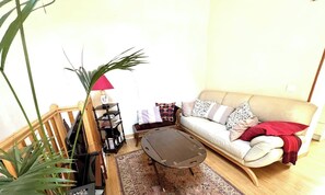 Ein Wohnzimmer mit einer Couch, einem Couchtisch, einem Bücherregal und einer Pflanze.