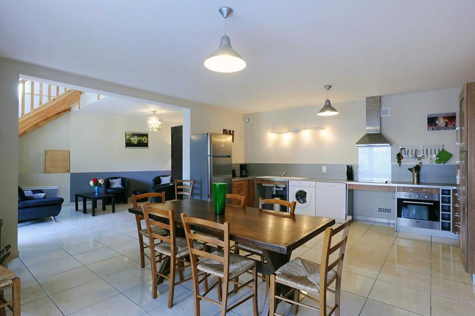 A modern kitchen with a dining area, a built-in oven, and a staircase leading to an upper level.