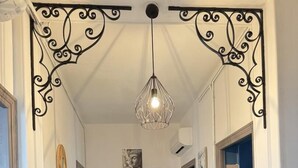 Ein Flur mit gemusterten Bodenfliesen, einem Holzschrank, einer Tür mit Milchglasfüllung und einer Pendelleuchte.