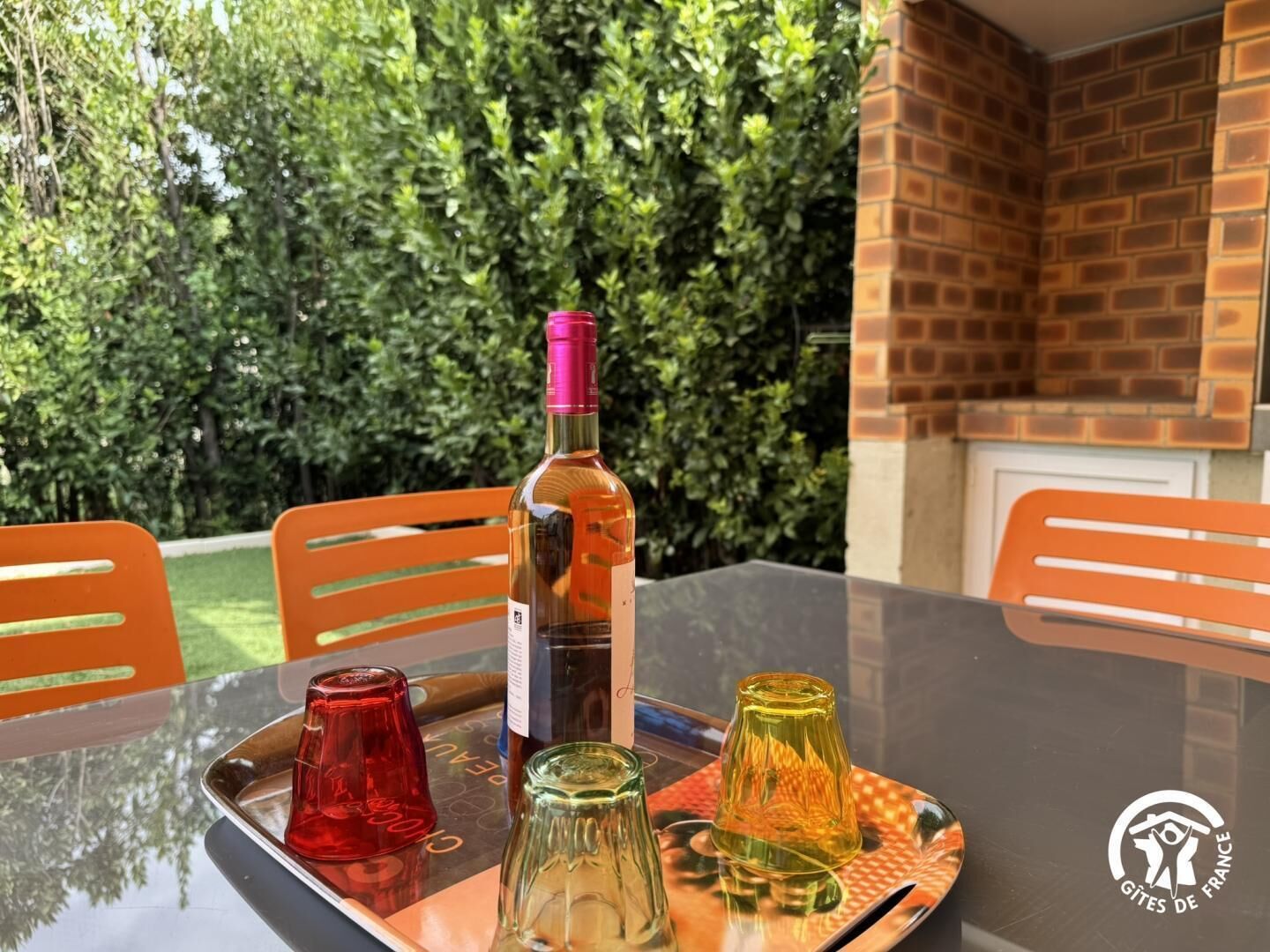 Une table avec une bouteille, deux verres et un plateau.