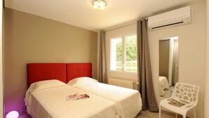 A bedroom with two beds, a red headboard, a white chair, and a window with curtains. - Carène - ARGELES-SUR-MER (ARGELES-SUR-MER)