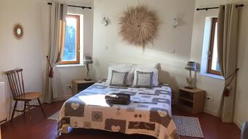 A bedroom with a large bed, two bedside tables, a chair, and a decorative wall piece.