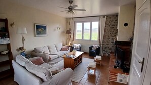 Una sala de estar con sofá, sillones, una mesa de centro, chimenea y ventilador de techo.