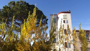 Un edificio con fachada curva, numerosas ventanas y tejado de tejas rojas.