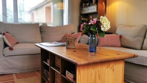 Una sala de estar con una mesa de centro de madera, un jarrón con flores y un sofá con cojines.