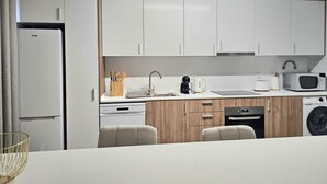 Une cuisine moderne avec des meubles blancs, un four à micro-ondes, une machine à café et un lave-vaisselle.