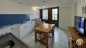 A compact kitchen with a dining area, a TV, and a green door. - Terrace - MONTALBA-LE-CHATEAU (MONTALBA-LE-CHATEAU)