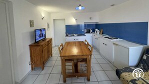 A compact kitchen with a wooden dining table, white cabinets, and a blue backsplash. - Terrace - MONTALBA-LE-CHATEAU (MONTALBA-LE-CHATEAU)