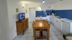 A compact kitchen with a wooden dining table, white cabinets, and a blue backsplash.