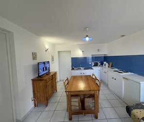 Une cuisine compacte avec une table à manger en bois, des placards blancs et un pare-feu bleu.