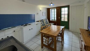 A compact kitchen with a dining area, a TV, and a green door.