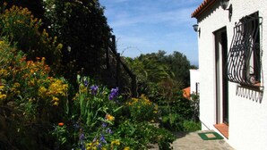 Un sentiero nel giardino conduce a un edificio bianco con tetto in tegole rosse.
