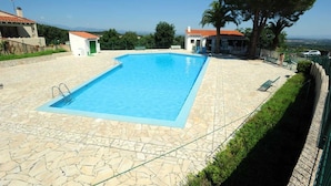 Una piscina rettangolare con bordo in pietra, circondata da un muretto basso e una recinzione metallica.