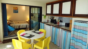 Una camera d'albergo compatta con angolo ristoro, angolo cottura e un letto vista.