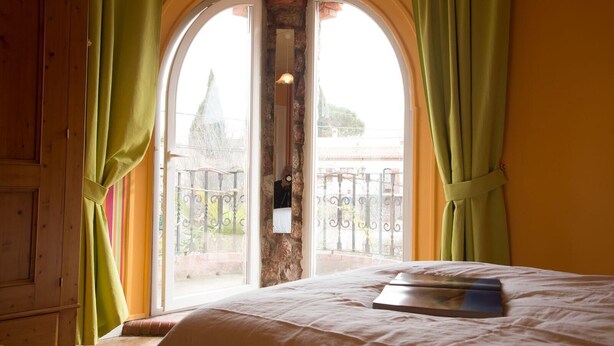 Une chambre avec un lit, une fenêtre donnant sur un balcon et des rideaux.