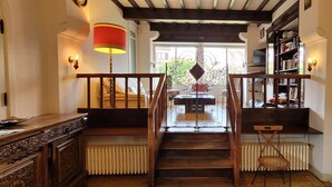 Un escalier en bois avec une rampe, un radiateur, une bibliothèque et une lampe.