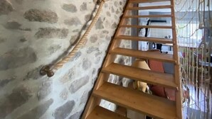 Eine Holztreppe mit Seilgeländer an einer Steinwand.