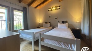 Ein Schlafzimmer mit zwei Betten, Holzboden und einem Balkon mit Aussicht.
