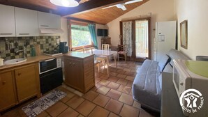A cozy kitchen with wooden cabinets, a dining area with a table and chairs, and a sofa.