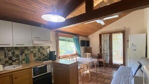 A cozy kitchen with wooden cabinets, a dining area with a table and chairs, and a sofa.
