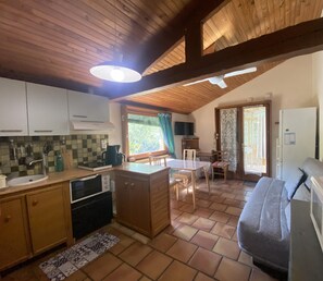 A cozy kitchen with wooden cabinets, a dining area with a table and chairs, and a sofa.
