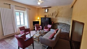 Una sala de estar con sofá, sillones, una mesita de centro, chimenea, televisor y ventilador de techo.