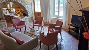 Una sala de estar con un arco de piedra, un sofá, dos sillones, una mesa de centro y una televisión.
