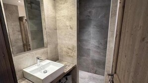 A modern bathroom with a large mirror, a built-in sink, and a shower area. - Gîte Sylvestre - LLO - Gîte (LLO)