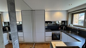 A modern kitchen with white cabinets, a black countertop, and a window. - Gîte Sylvestre - LLO - Gîte (LLO)