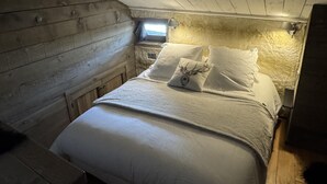 A cozy wooden cabin bedroom with a bed, pillows, and a window. - Gîte Sylvestre - LLO - Gîte (LLO)