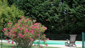 A fenced outdoor area with a pool, a chair, and a flowering shrub. - Les oliviers - THUIR (THUIR)