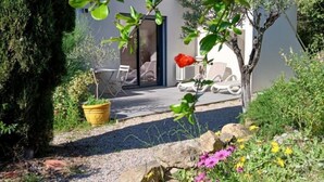 Un jardín con un sendero que lleva a un edificio con una puerta y una silla afuera.