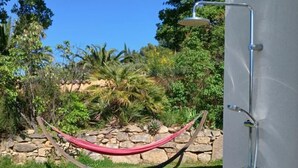 Una hamaca en un jardín con un cabezal de ducha en la pared.