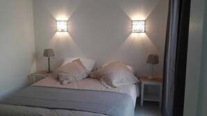 Un dormitorio con una cama, dos mesitas de noche y dos lámparas de pared.