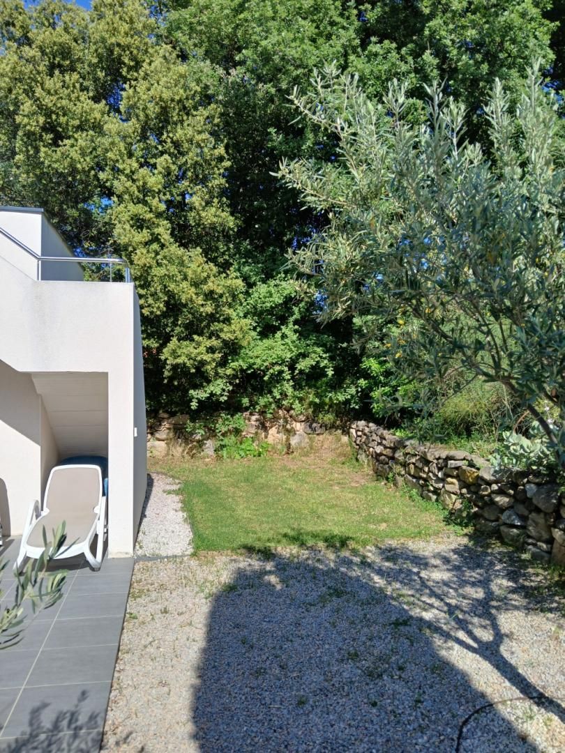 A modern outdoor patio with a white chair, a small table, and a stone wall.