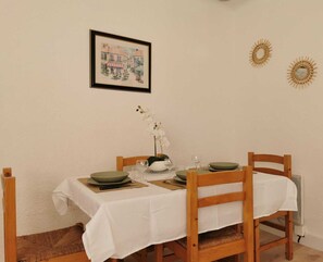 Un comedor con una mesa lista para dos personas, un cuadro en la pared y dos adornos de pared.