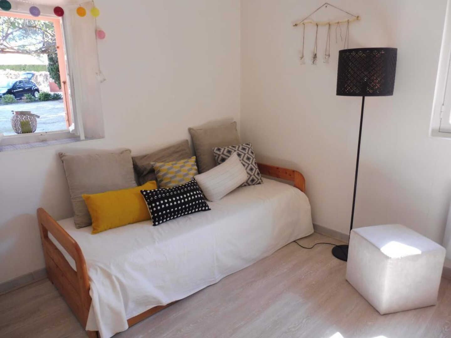 A cozy room with a wooden bed, a white bedside table, and a floor lamp.