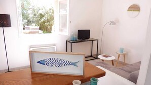 A modern living room with a wooden coffee table, a framed fish artwork, a television, and a small side table with a blue vase.