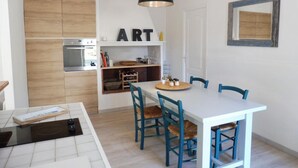 A modern kitchen with a built-in oven, a dining table with chairs, and a pendant light.