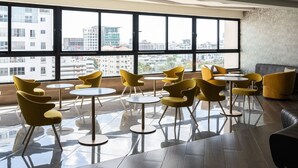 Ein modernes Interieur mit großen Fenstern, gelben Stühlen und einem spiegelnden Boden.